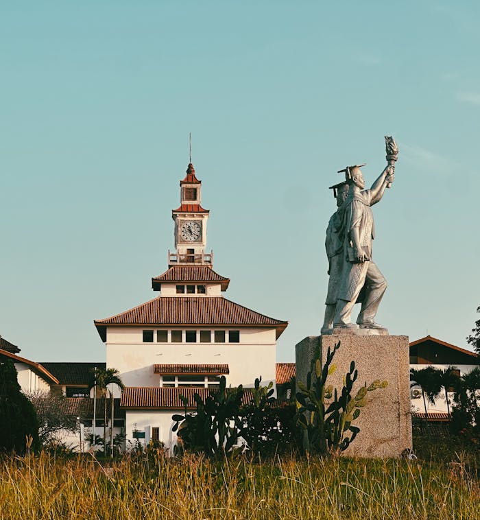 A prominent statue and clock tower on a university campus during the day.